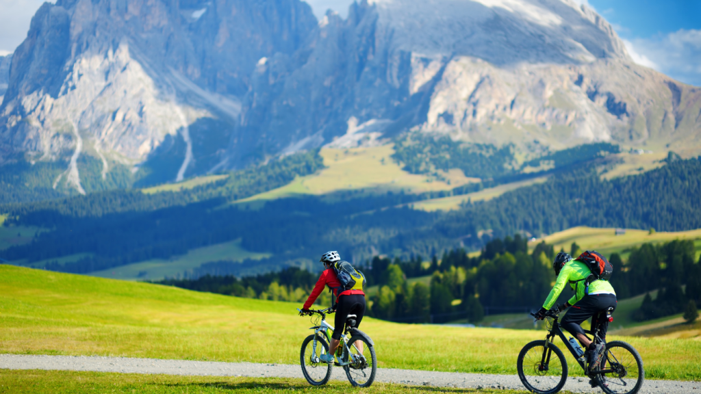 Two friends travelling on a scenic and lush cycle route in France, with a magnificent mountain in the background.
