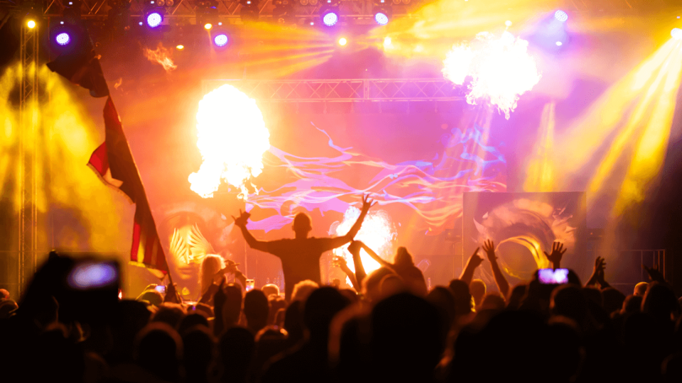 Crowd cheering at a concer with colorful stage lights